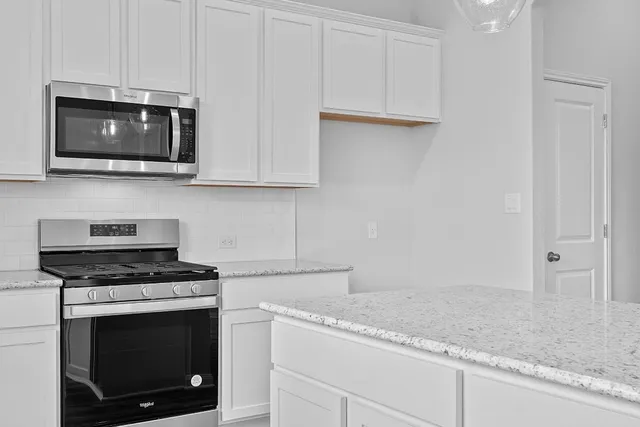 a kitchen with granite countertop white cabinets and stainless steel appliances