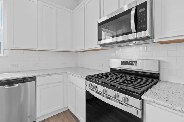 a kitchen with white cabinets and appliances