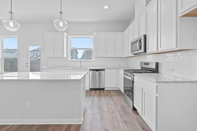 a kitchen with cabinets wooden floor and stainless steel appliances