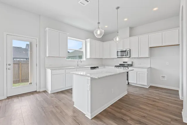 a kitchen with white cabinets stainless steel appliances and wooden floor