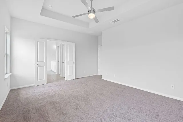 an empty room with closet and a ceiling fan