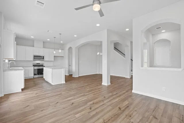 an open kitchen with kitchen island white cabinets and wooden floor