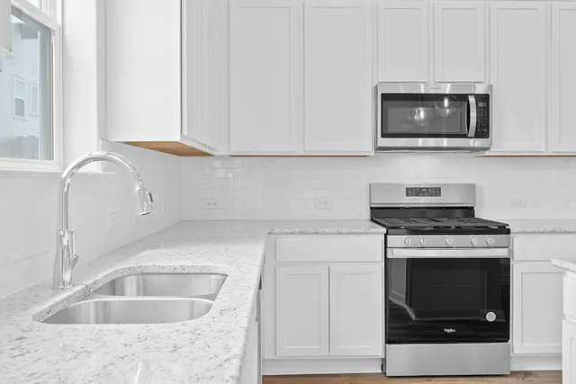 a kitchen with granite countertop a stove top oven microwave and cabinets