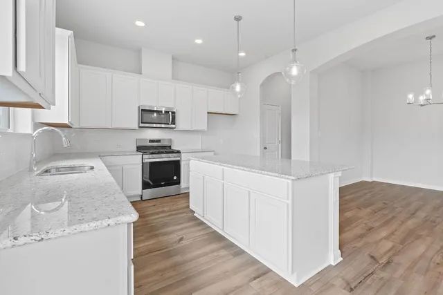 a kitchen with granite countertop a sink cabinets and stainless steel appliances