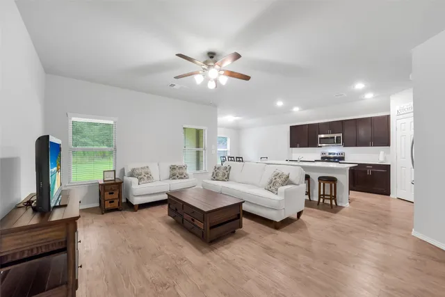 a living room with furniture kitchen view and a large window