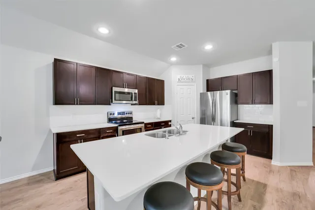a kitchen with stainless steel appliances a stove refrigerator sink and table