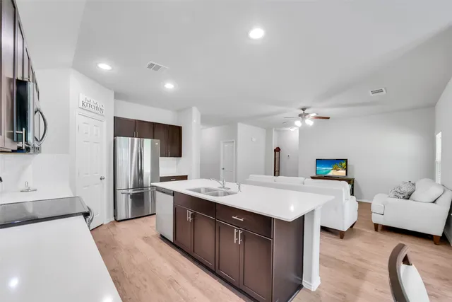a large kitchen with stainless steel appliances kitchen island granite countertop a refrigerator and a sink
