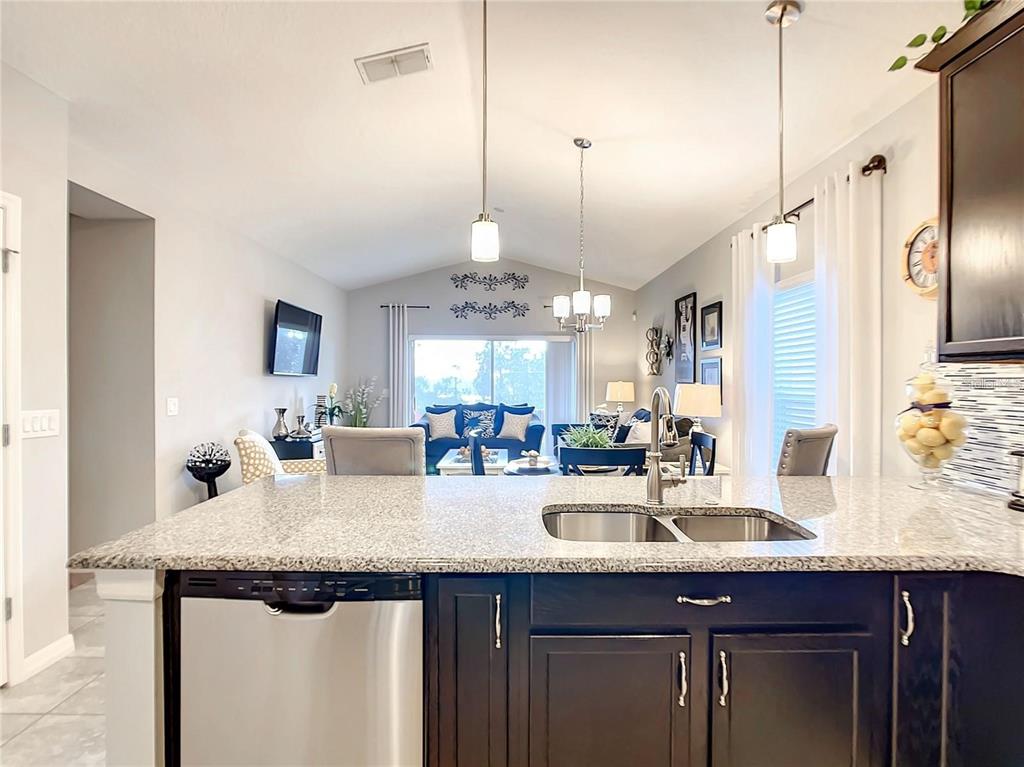 1300 Cavender Creek Road Minneola, FL 34715 - Photo 3 of 28 a kitchen with kitchen island granite countertop a sink a counter space appliances and cabinets