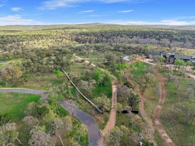 an aerial view of residential houses with outdoor space and trees
