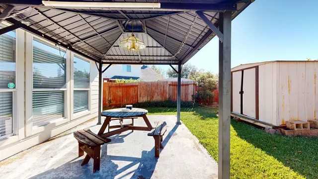 a view of a patio with table and chairs under an umbrella with a small yard