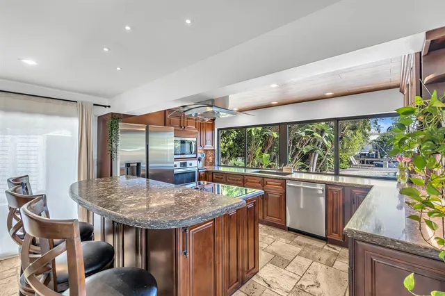 a kitchen with stainless steel appliances granite countertop a stove a refrigerator a dining table and chairs with wooden floor