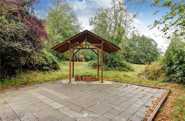 a backyard of a house with table and chairs under an umbrella