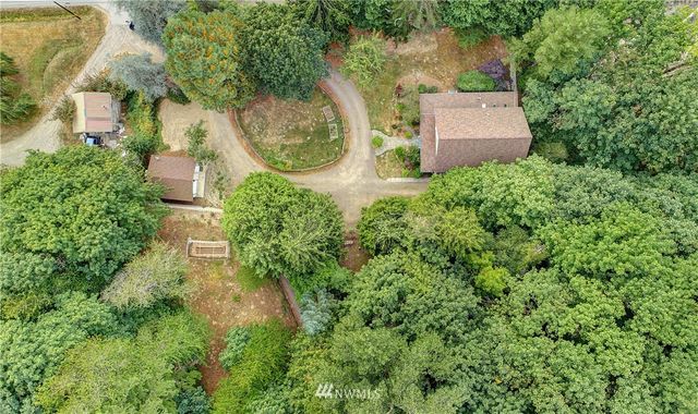 an aerial view of a house with outdoor space and trees all around
