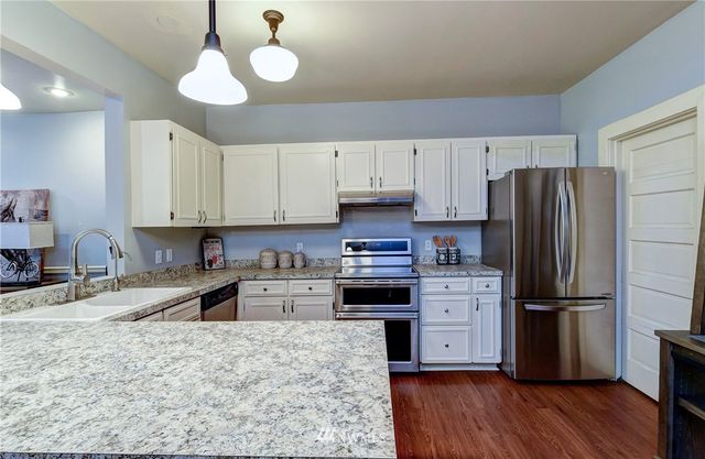 a kitchen with granite countertop a refrigerator stove and sink