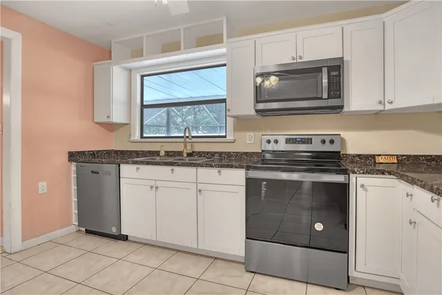 a kitchen with granite countertop white cabinets stainless steel appliances and a sink