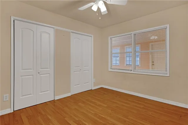 a view of empty room with wooden floor and fan