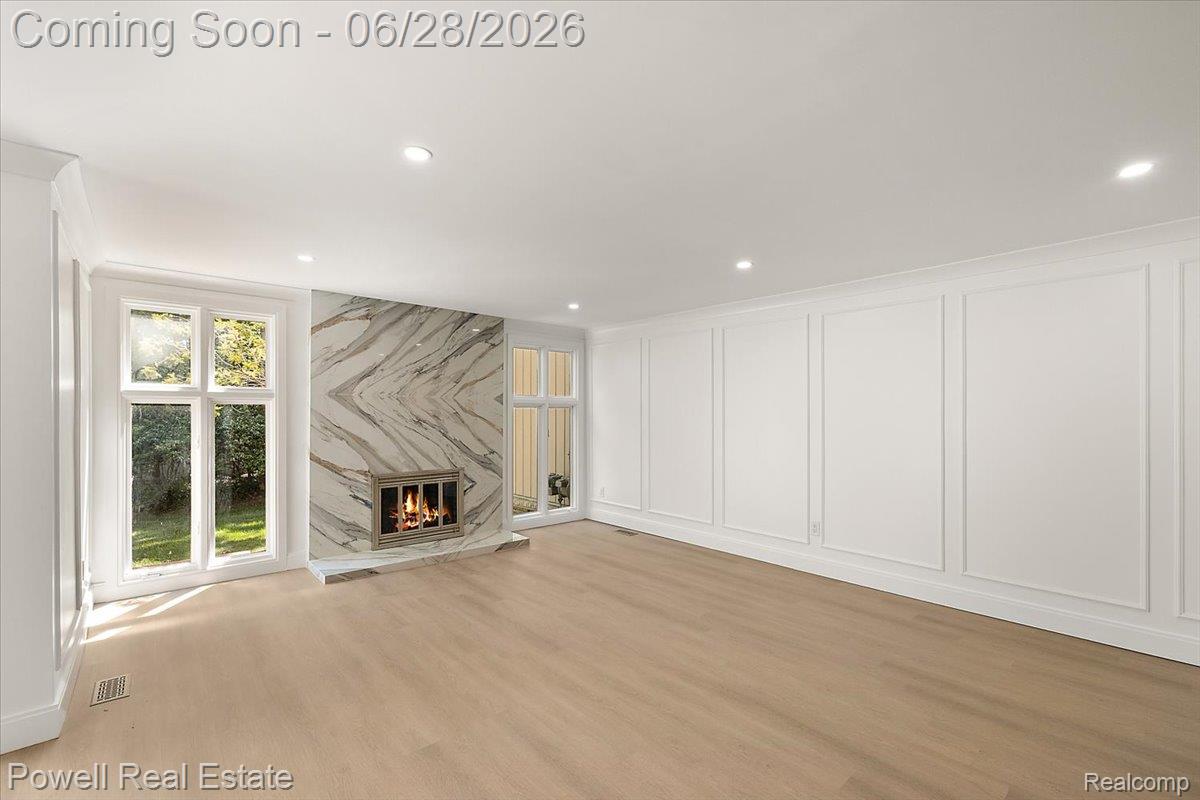 1447 Ravineview Court, Unit C12 Bloomfield Hills, MI 48304 - Photo 15 of 49 Spacious room featuring a striking fireplace with a symmetrical stone surround, light wood-finish flooring, recessed lighting, and wall panel molding