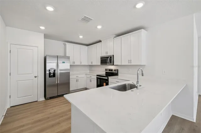 a kitchen with a refrigerator a sink dishwasher and a refrigerator with wooden floor