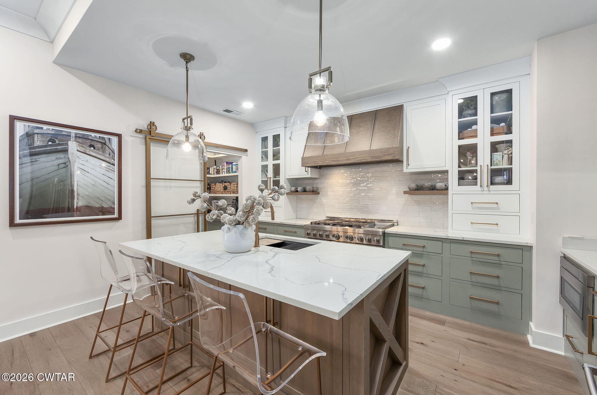 a kitchen with a stove a sink a kitchen island with chairs and wooden cabinets