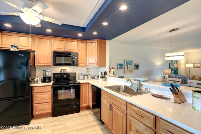 a kitchen with stainless steel appliances granite countertop a refrigerator a sink dishwasher a stove and white countertops with wooden floor