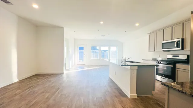 a kitchen with stainless steel appliances granite countertop a stove top oven a sink dishwasher and a microwave oven with wooden floor