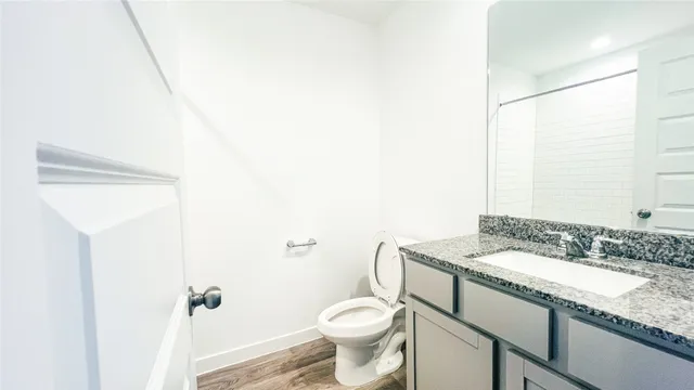 a bathroom with a granite countertop sink toilet and a mirror