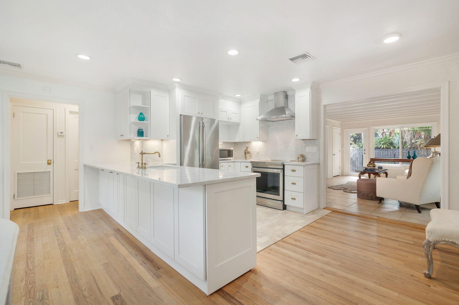 240 Almeria Road West Palm Beach, FL 33405 - Photo 7 of 24 an open kitchen with white cabinets and stainless steel appliances