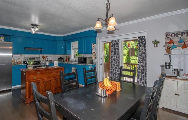 a kitchen with stainless steel appliances granite countertop a dining table chairs and chandelier