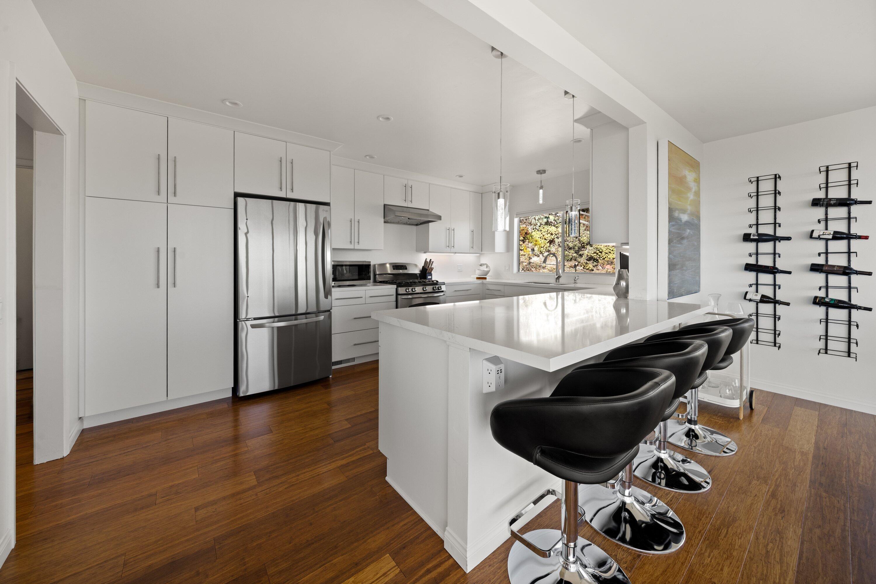 128 Las Alturas Road Santa Barbara, CA 93103 - Photo 10 of 34 a kitchen with stainless steel appliances kitchen island granite countertop a table chairs in it and wooden floors
