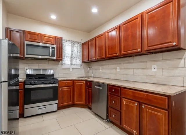 a kitchen with stainless steel appliances granite countertop wooden cabinets a stove a sink and a microwave