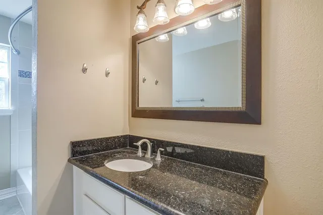 a bathroom with a granite countertop sink and a mirror