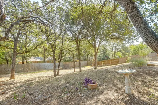 a backyard of a house with wooden fence and large trees