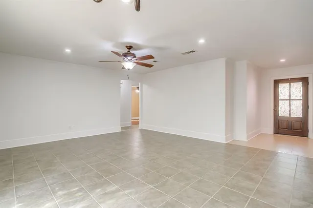 a view of an empty room with a ceiling fan and window