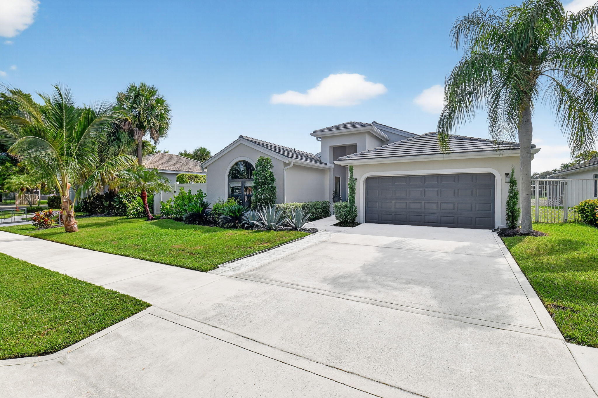 1175 Sea Grape Circle Delray Beach, FL 33445 - Photo 3 of 64 a front view of a house with a garden and palm trees