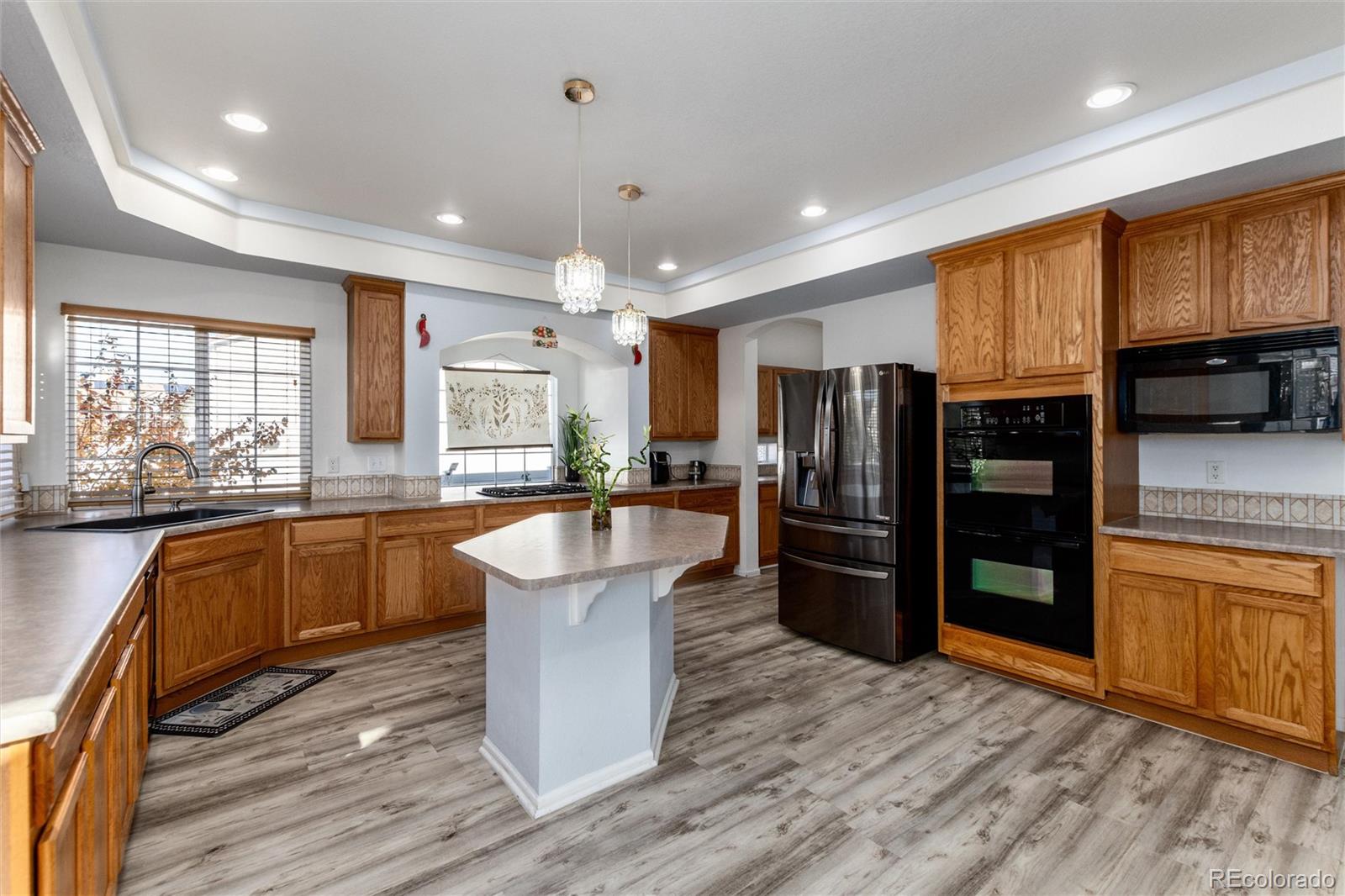 5293 Malaya Street Denver, CO 80249 - Photo 19 of 44 a kitchen with stainless steel appliances granite countertop a refrigerator a sink dishwasher a stove and white countertops with wooden floor