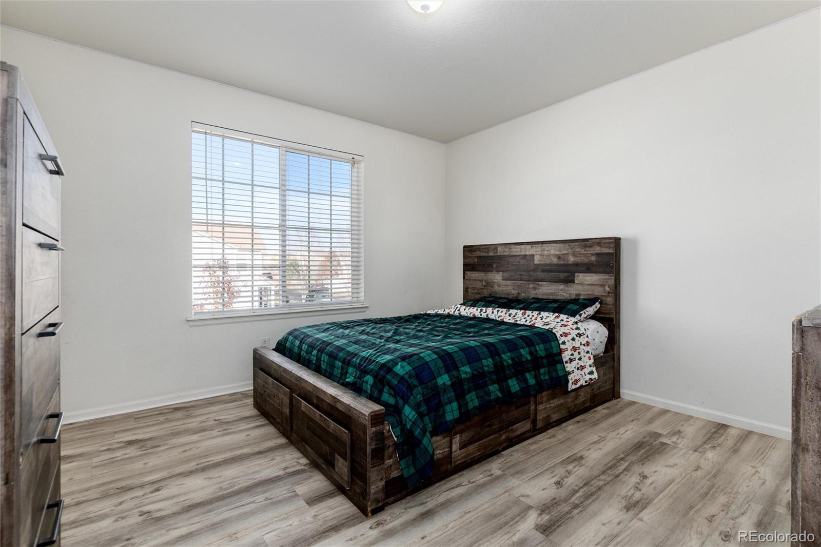 5293 Malaya Street Denver, CO 80249 - Photo 28 of 44 a bedroom with a bed and wooden floor