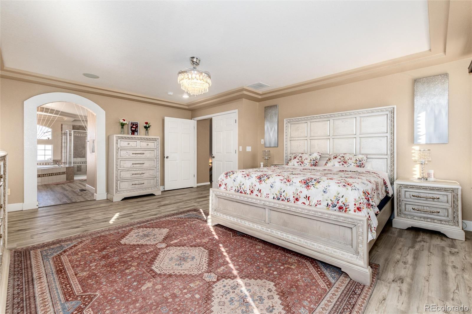 5293 Malaya Street Denver, CO 80249 - Photo 30 of 44 a bedroom with a large bed and a chandelier