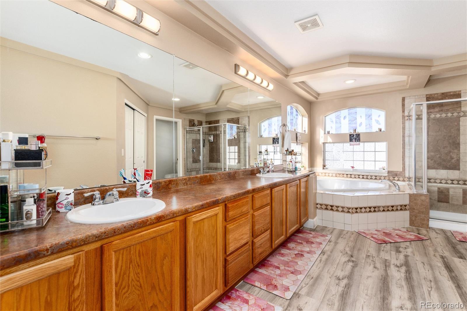 5293 Malaya Street Denver, CO 80249 - Photo 33 of 44 a large bathroom with a double vanity sink a mirror and a bathtub