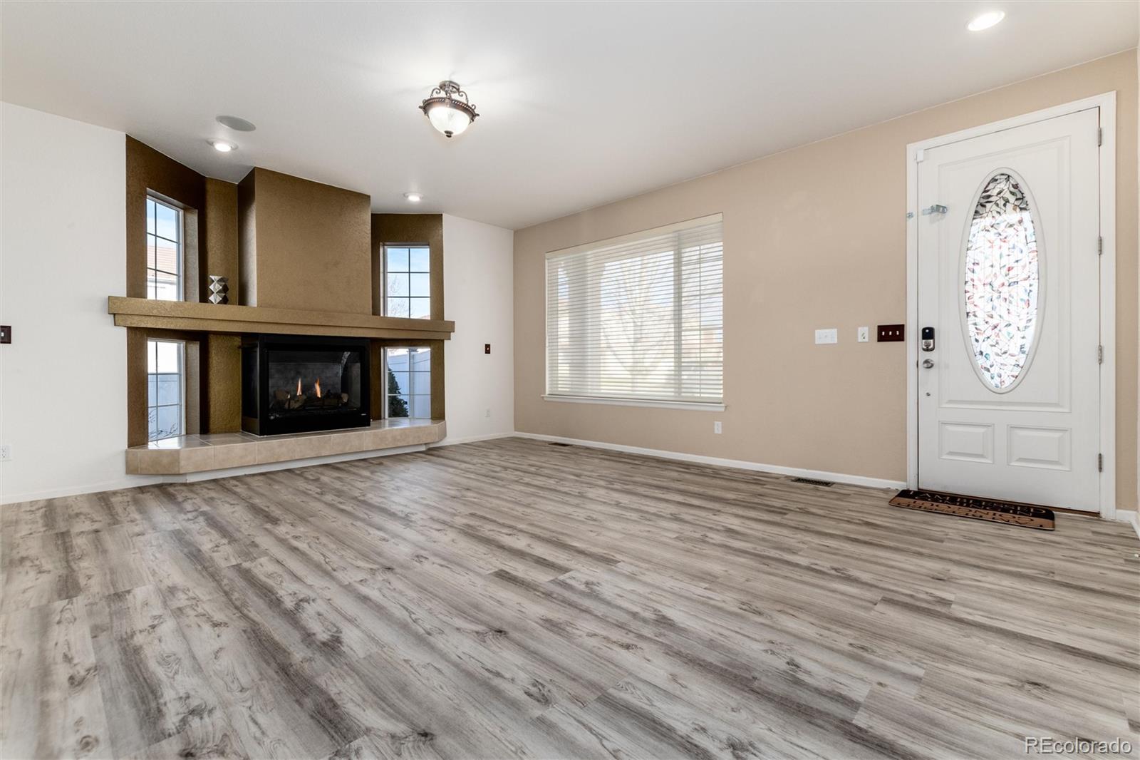 5293 Malaya Street Denver, CO 80249 - Photo 7 of 44 an empty room with windows fireplace and wooden floor
