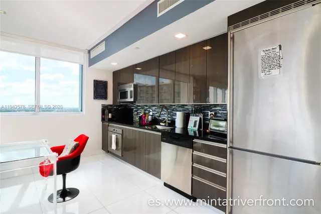 a kitchen with stainless steel appliances kitchen island granite countertop a refrigerator and a stove top oven