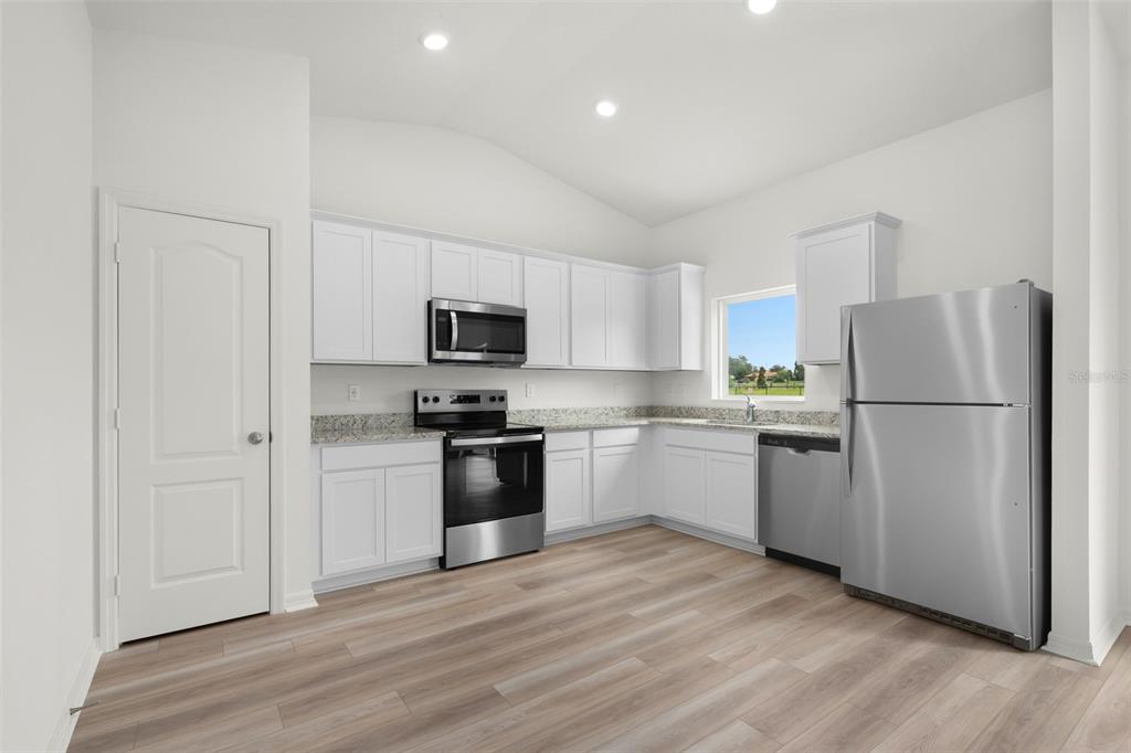 13438 Leaping Water Way Astatula, FL 34705 - Photo 3 of 18 a kitchen with a refrigerator stove and white cabinets