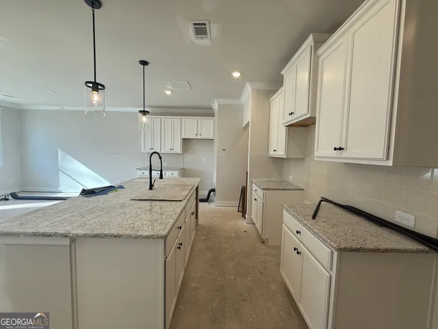 a kitchen with white cabinets sink and stove