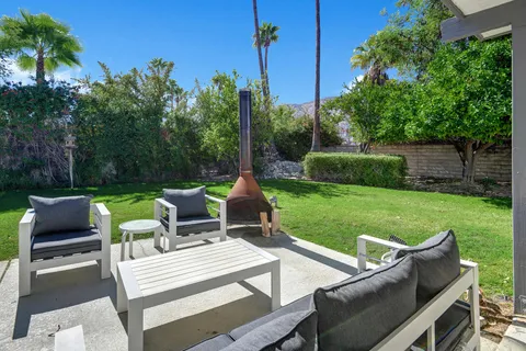 a view of a patio with table and chairs potted plants and palm tree