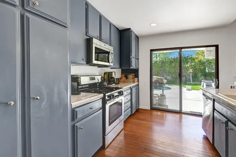 a kitchen with stainless steel appliances granite countertop a stove a sink and a microwave