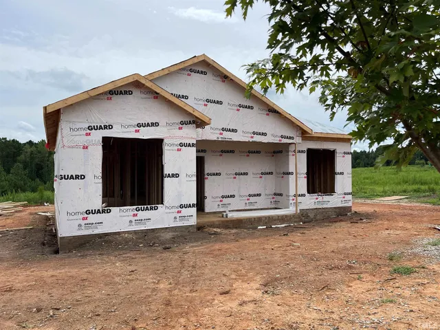 a view of a house with large tree and wooden fence