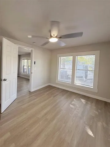 a view of an empty room with a window and wooden floor