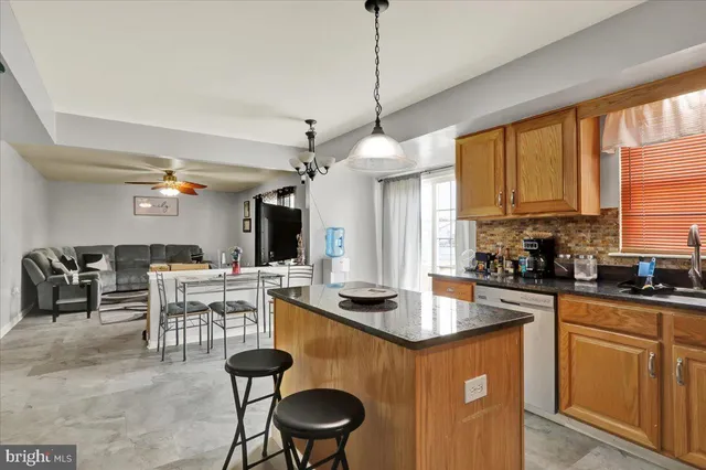 a kitchen with granite countertop a stove a sink a dining table and chairs