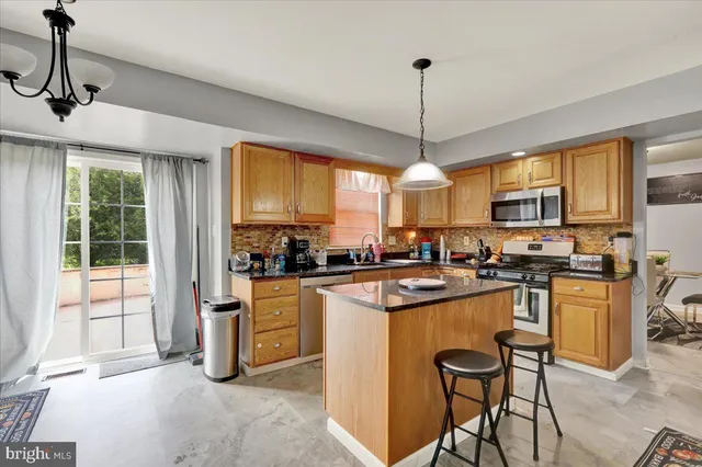 a kitchen with stainless steel appliances granite countertop a stove top oven a refrigerator a sink dishwasher a dining table and chairs with wooden floor