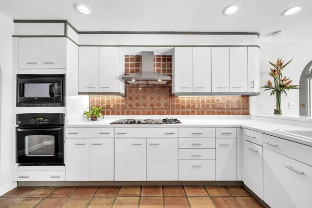 a kitchen with cabinets appliances a sink and a window