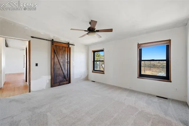 a view of a livingroom with a chandelier fan and windows